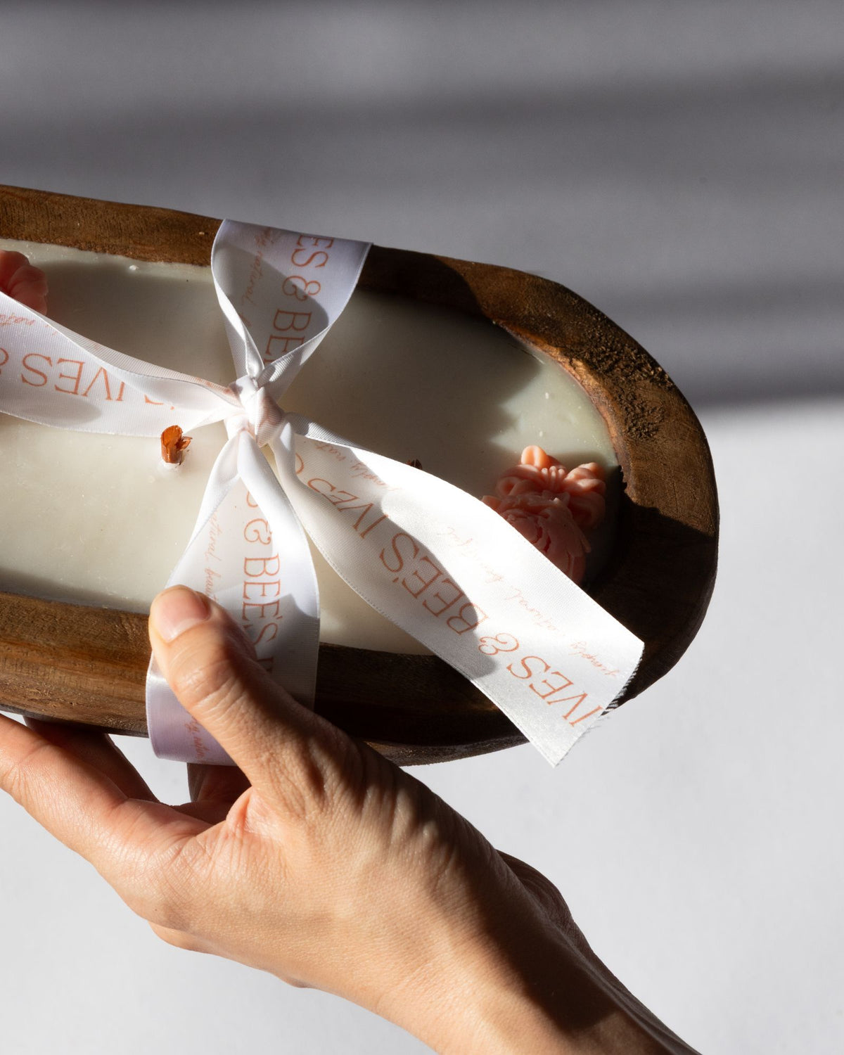 Hand holding a wrapped product with a visible brand name against a neutral background