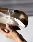 Hand holding a wrapped product with a visible brand name against a neutral background