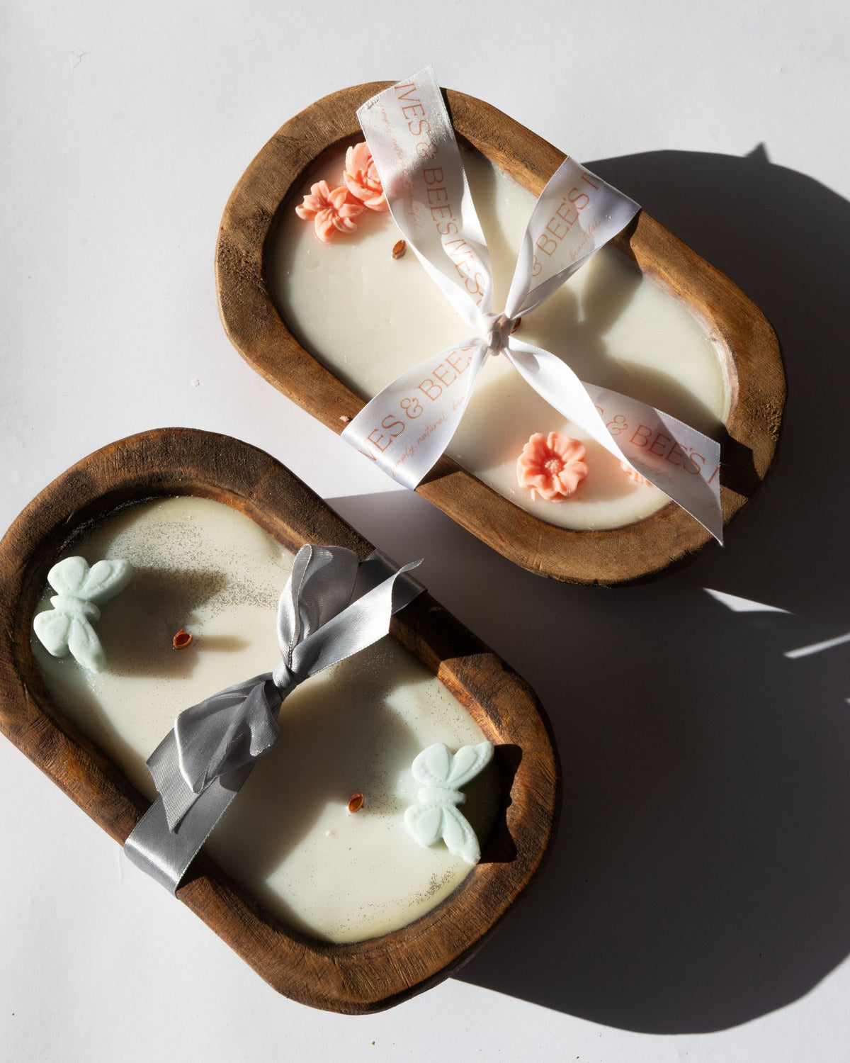 Two heart-shaped candles with decorative ribbons on a white background