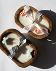 Two heart-shaped candles with decorative ribbons on a white background