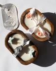 Two small candles in wooden holders with decorative ribbons on a light background