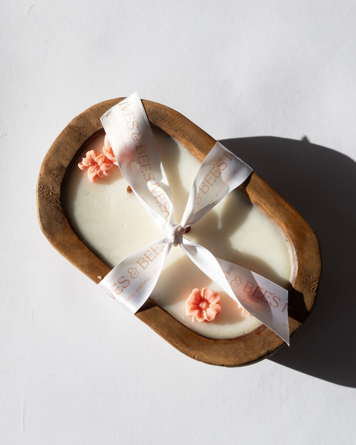 Bulaklak Wooden Bowl Candle in a wooden mold with decorative flowers and a ribbon on a light background