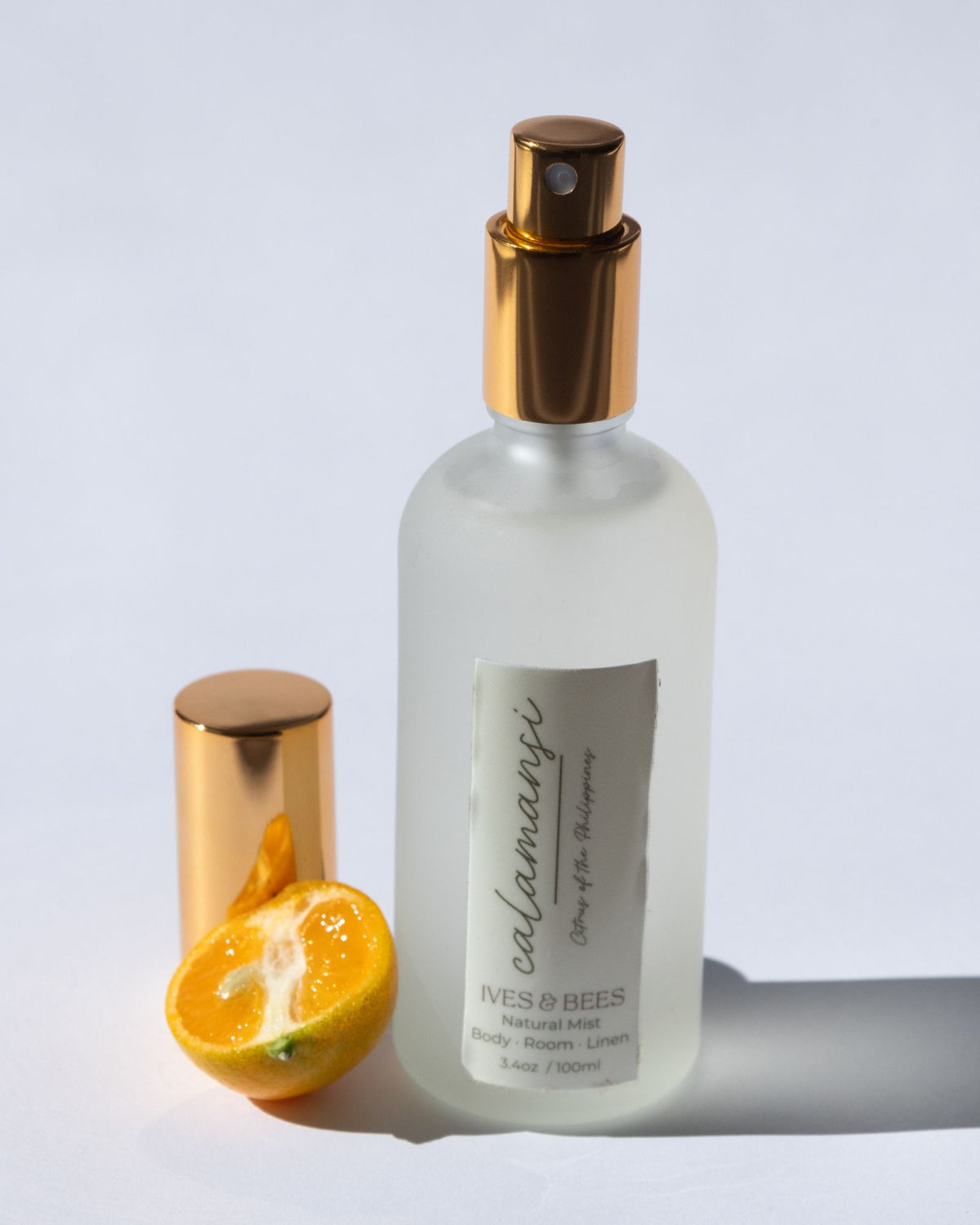 Handmade Natural Mist with gold cap and orange half on a light gray background