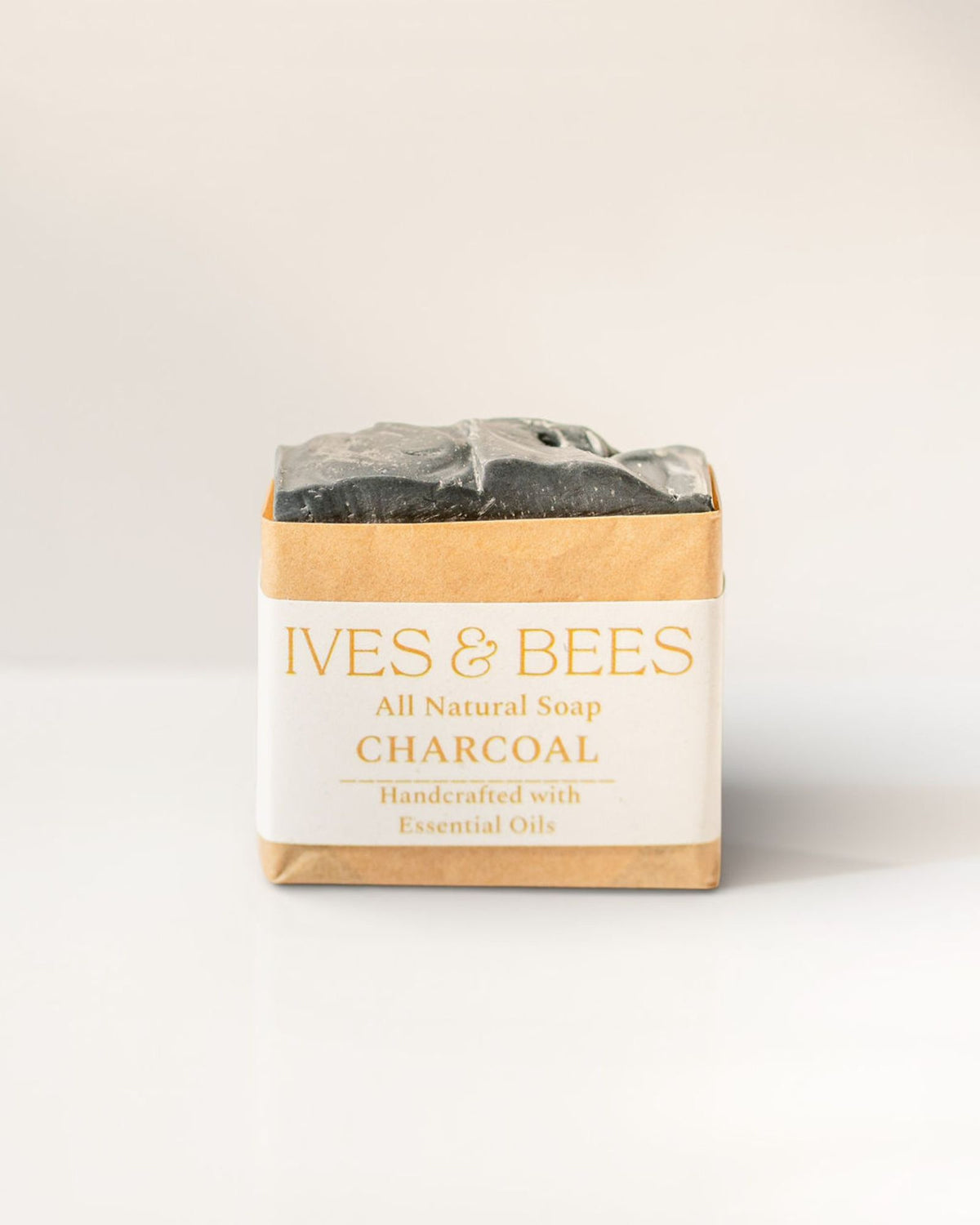 Bar of charcoal soap with 'Ives & Bees' packaging on a white background