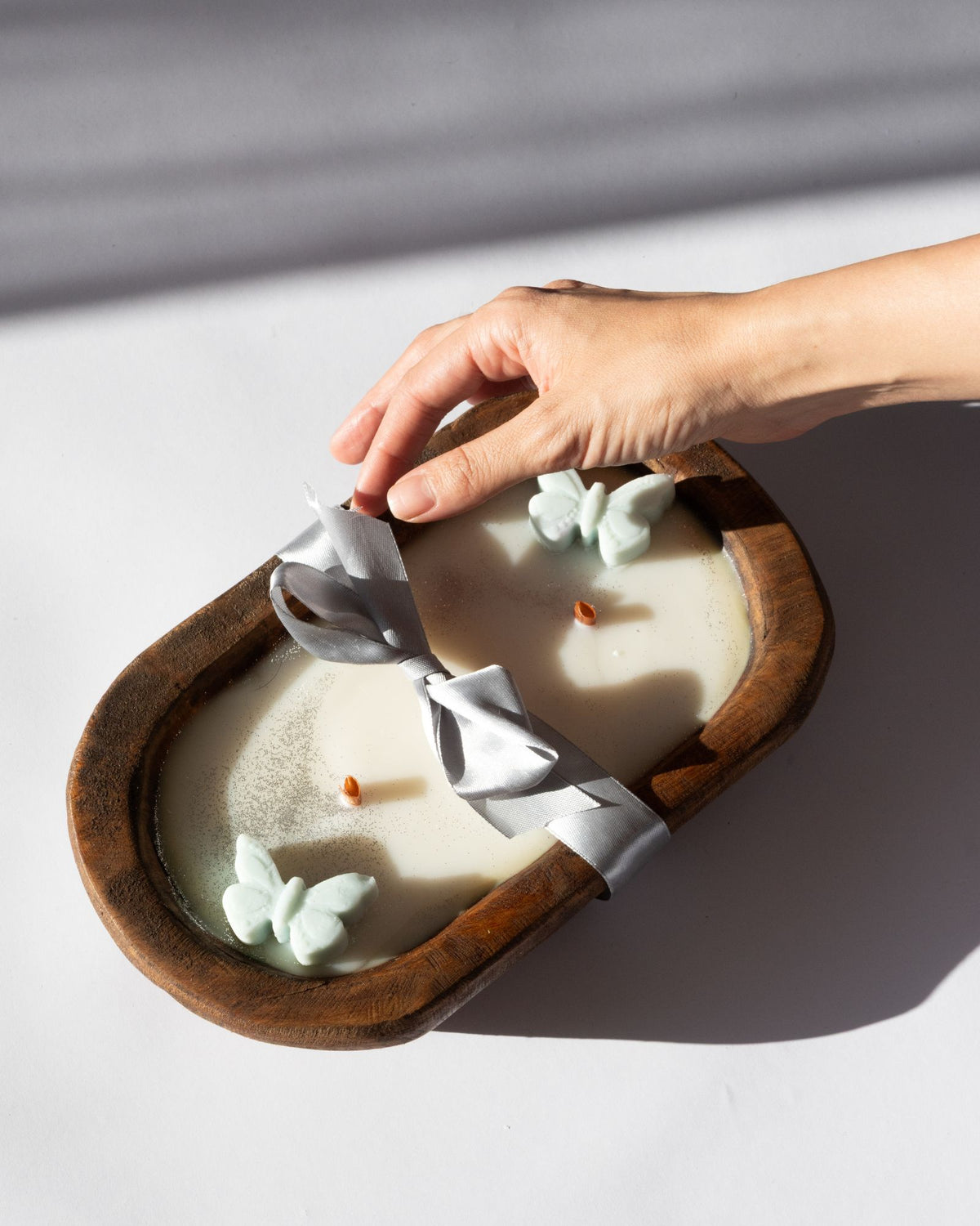 Hand interacting with a Diwata Wooden Bowl Candle