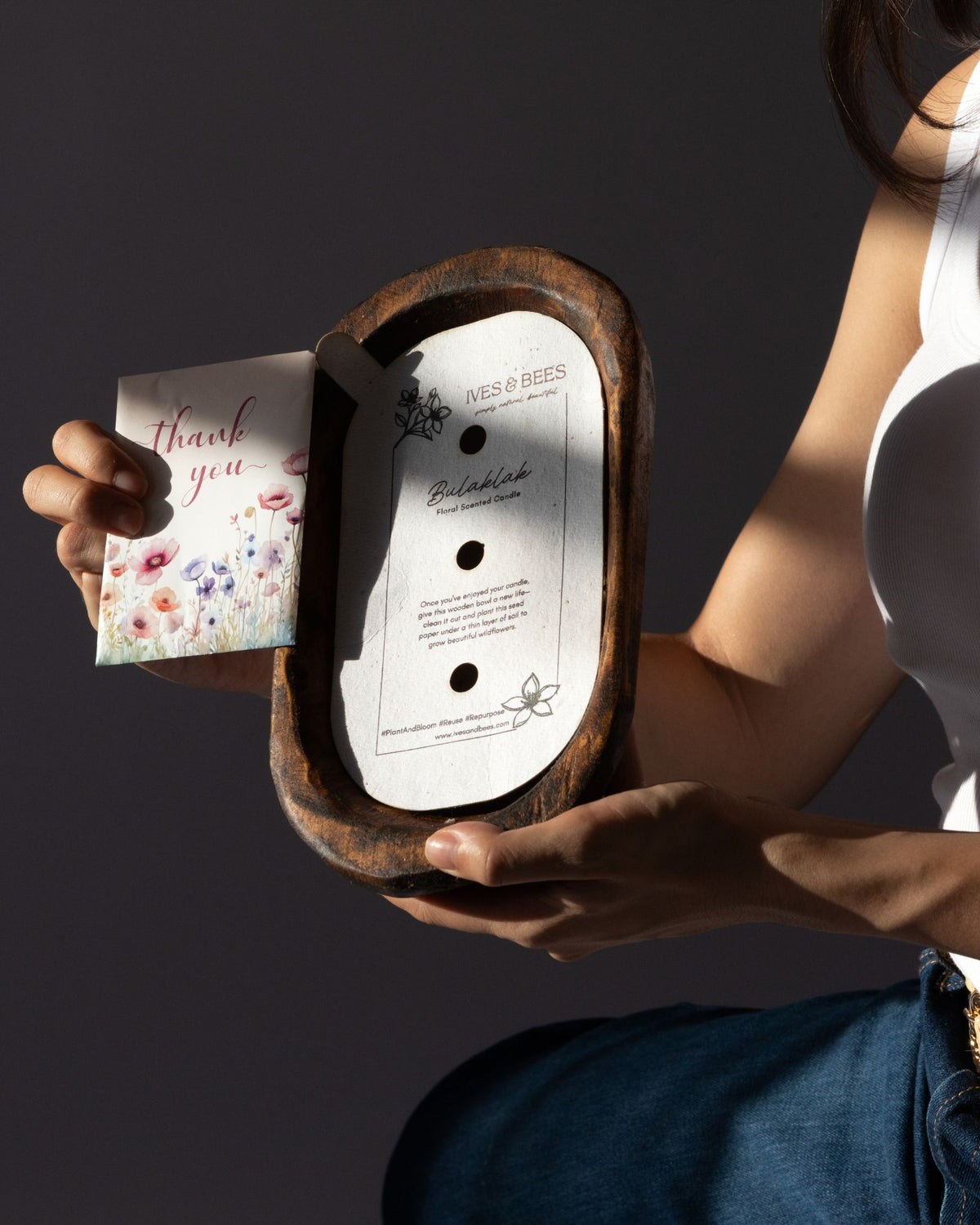 Person holding a Diwata Wooden Bowl Candle with a card featuring 'thank you' text on a dark background