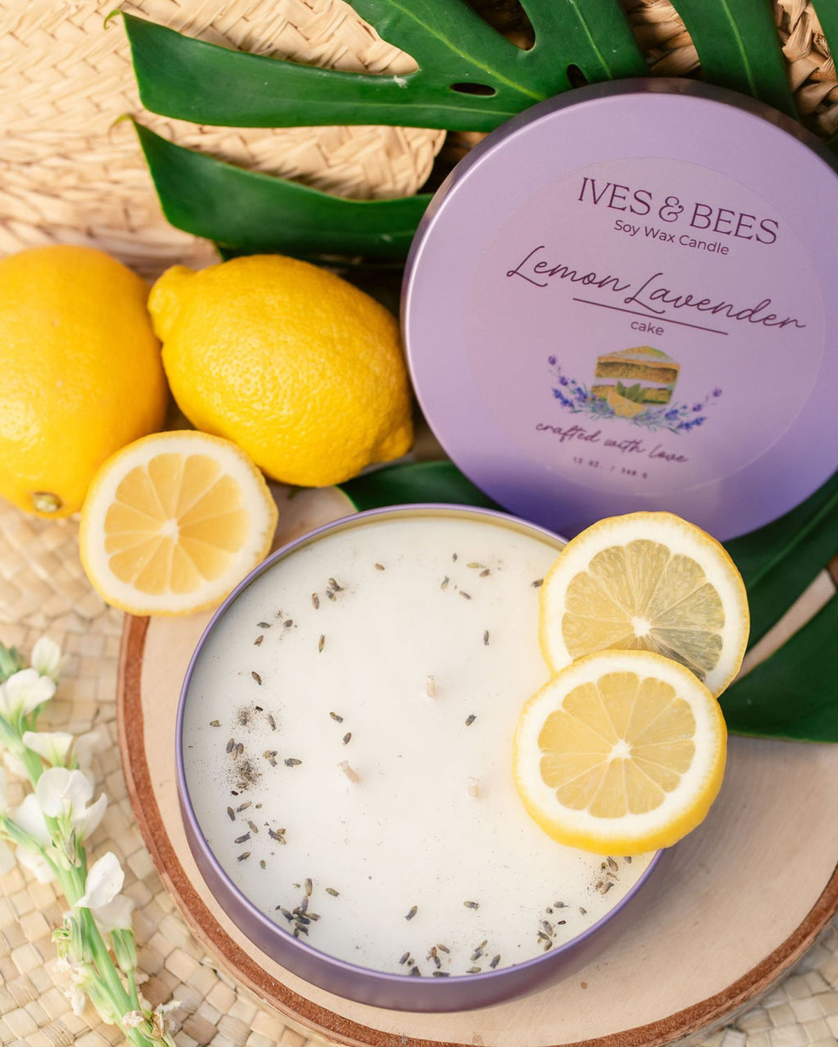 Lemon Lavender Cake Candle with lemons and green leaves on a woven surface