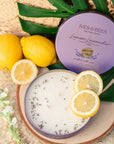 Lemon Lavender Cake Candle with lemons and green leaves on a woven surface
