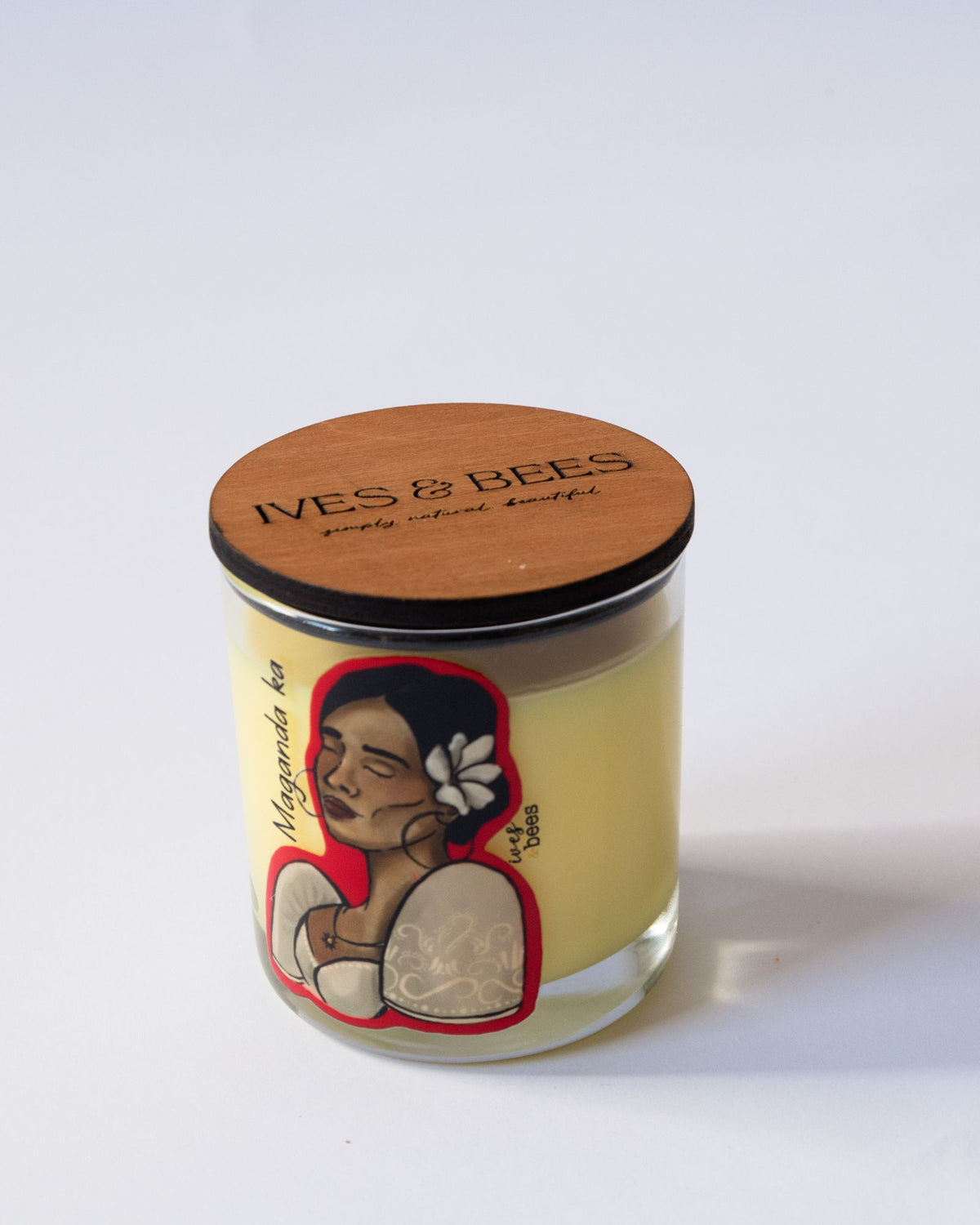 Maganda Ka Candle with a wooden lid featuring a design of a woman with a flower in her hair on a white background.