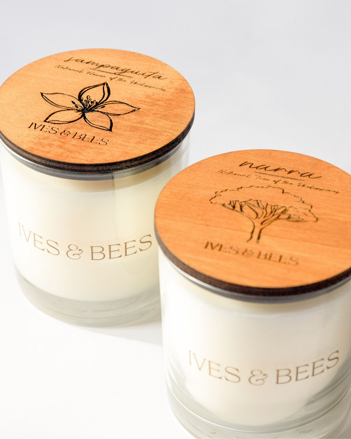 Sampaguita Candle & Narra Candle Duo with round engraved wooden lids, photographed on a clean white background. 